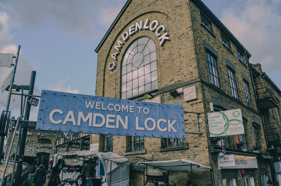 The photograph depicts a multi-story brick building labeled 'Camden Lock' with large arched windows on the upper floor and smaller rectangular windows on the lower floors. A prominent blue sign with w